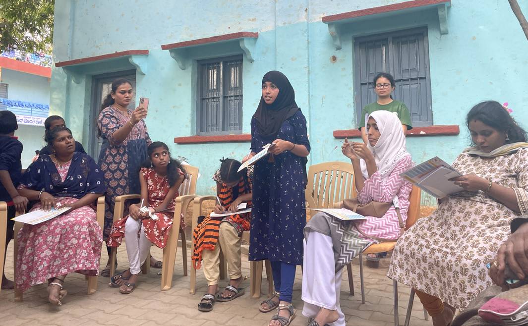 Women in a neighbourhood meeting reading out community findings