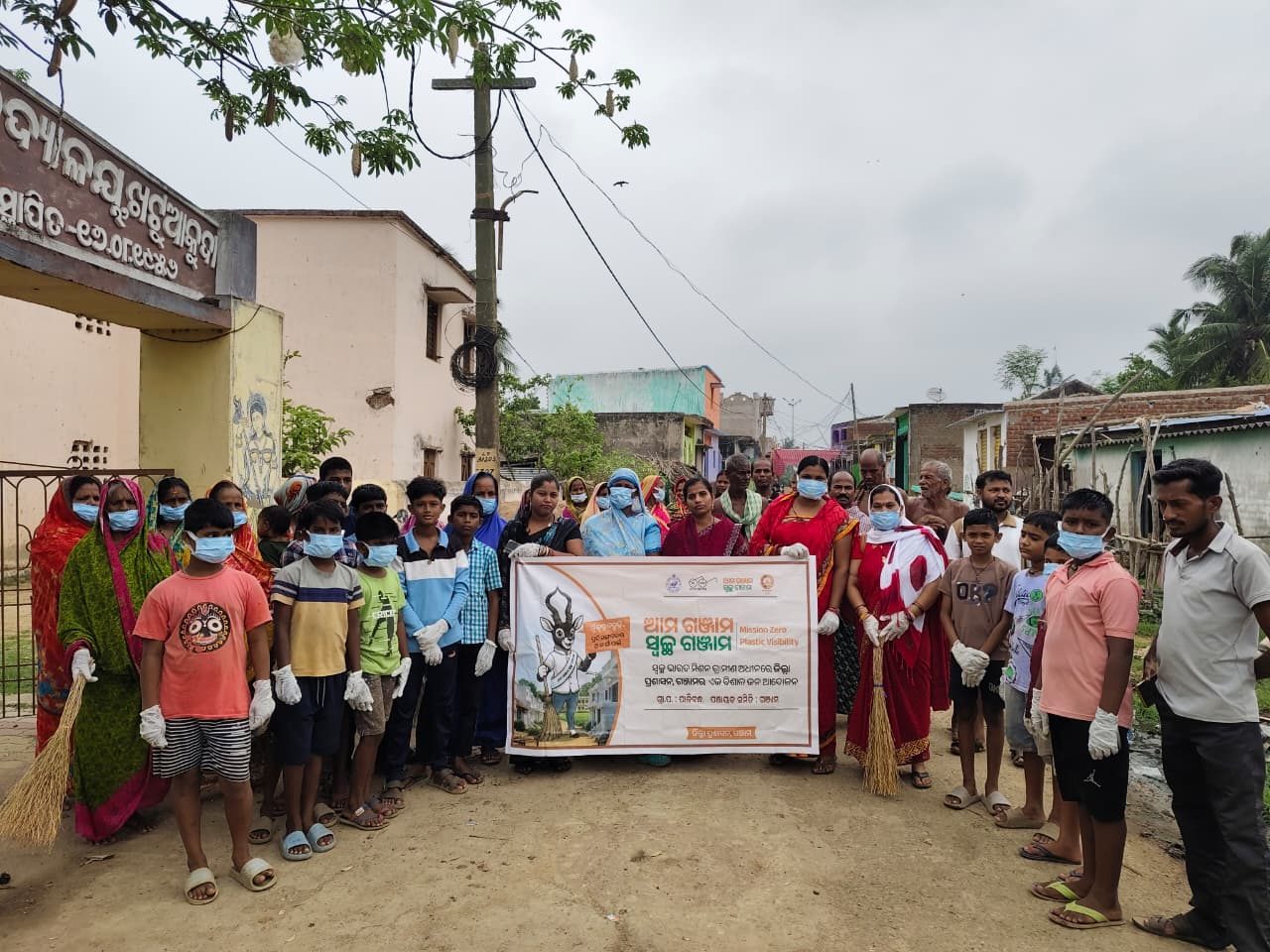 Villagers and children with brooms at a clean-up campaign