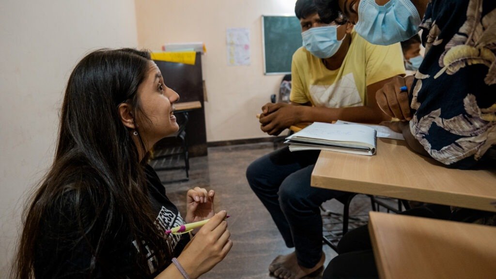 Devika talking with young people at their desks